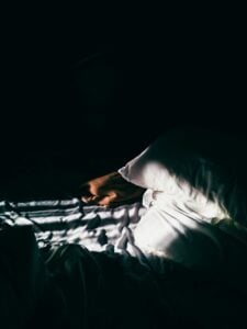 Very dark room with sunlight appearing on a unmade bed